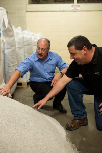 Heritage Glass CEO Chris Cording, left, and President Eric Kerney sift through Italian dolomite -- one of several raw materials used in glassmaking -- left over from the AGC Glass days. (Photo by Adam Campbell)